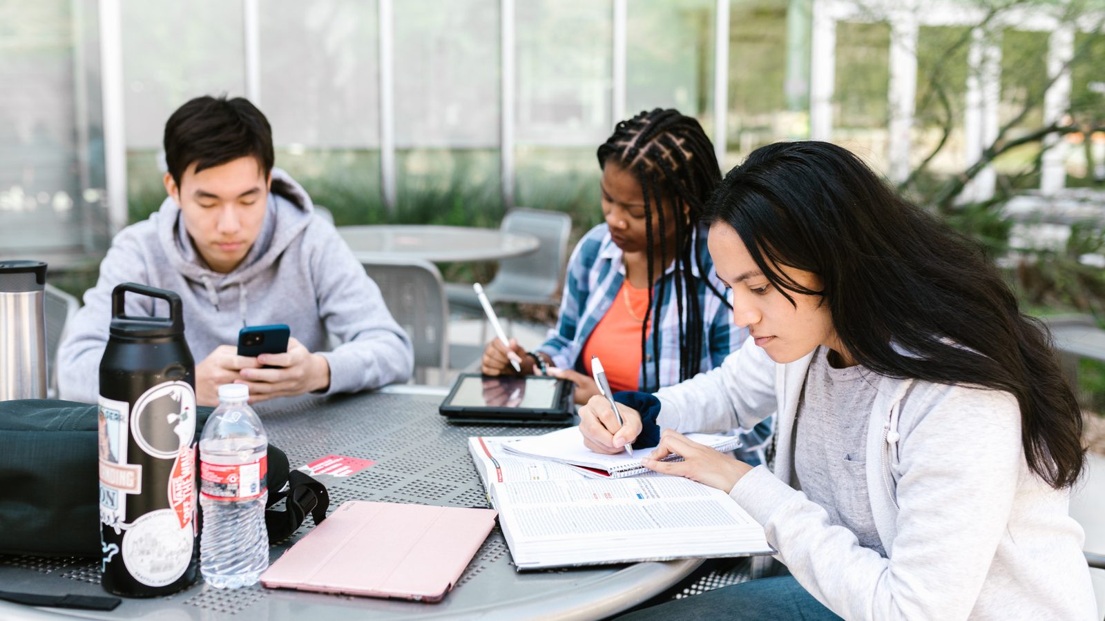 Students at an outdoor table with phones and notebooks